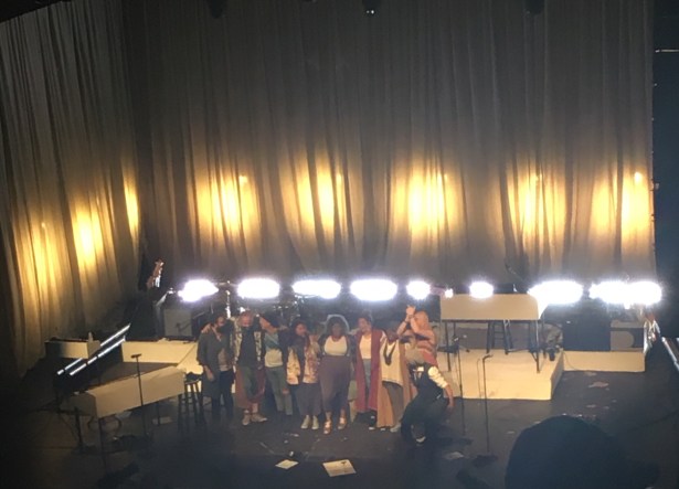 nine people standing on stage facing audience
