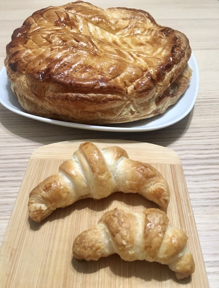 large puff pastry cake on plate and two small croissants on serving board