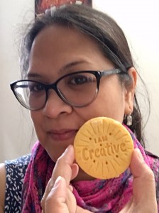 woman wearing glasses and holding round lemon cookie with words I am creative on it