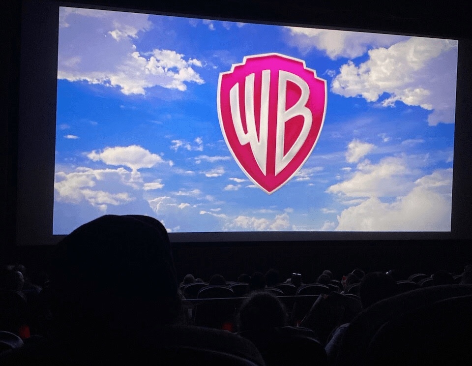 movie screen with blue sky white clouds and a shield with the letters WB