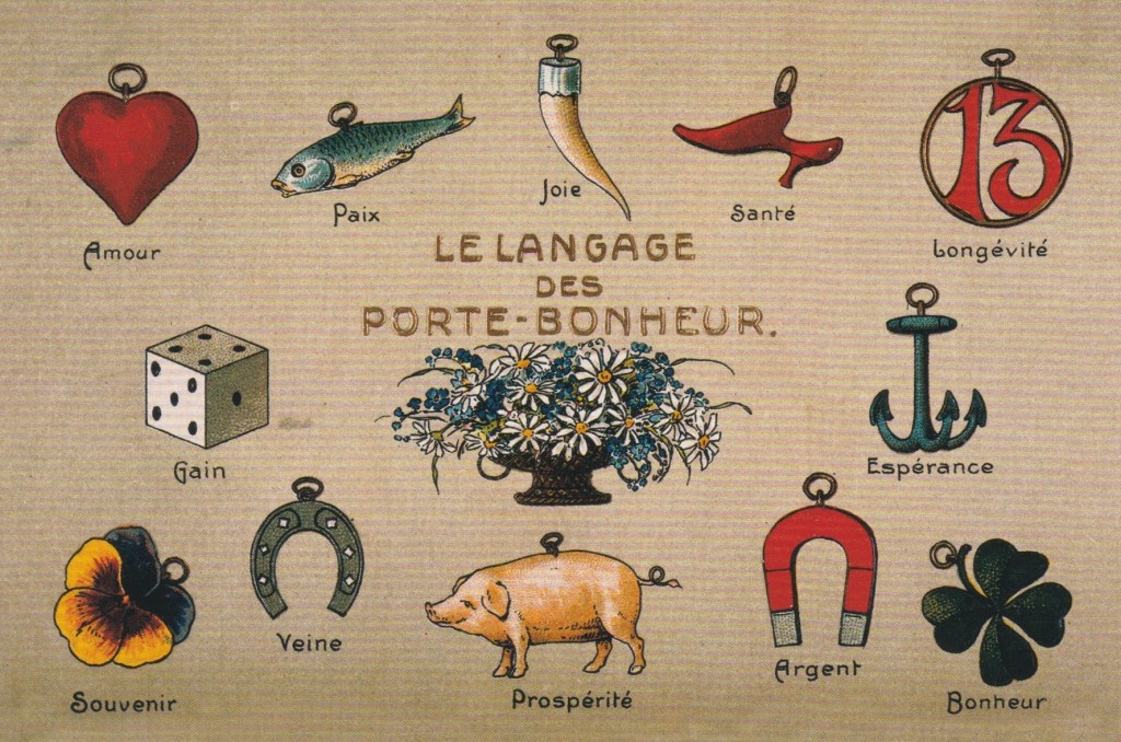 French text says le langage des porte-bonheur with pictures of red heart, blue fish, tiger tooth, red shoe, number 13 in a circle, a die with 10 dots, a vase with flowers, anchor, pansy, horseshoe, pig, magnet, four-leaf clover