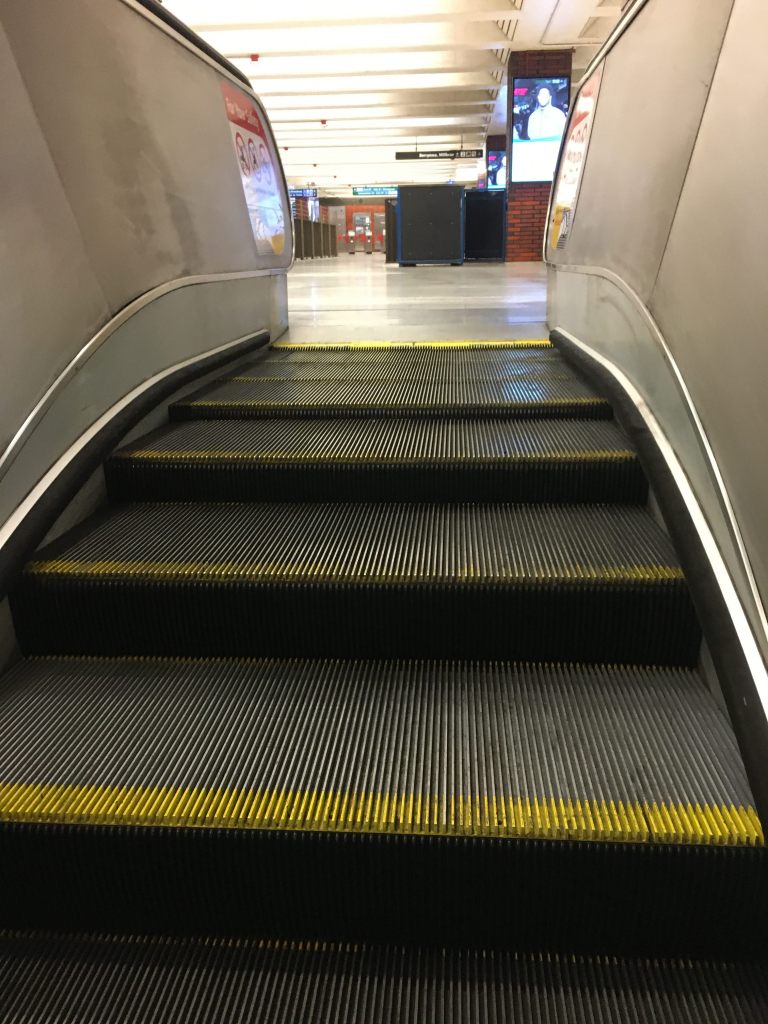 escalator steps leading up to the floor of subway station