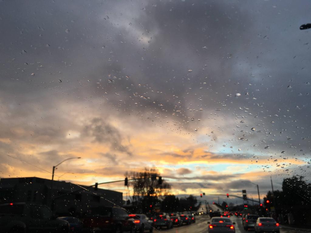 raindrops on windshield at sunset blue sky with orange and pink clouds